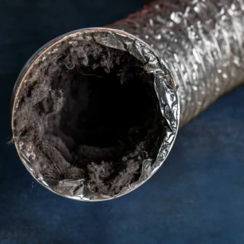 Close-up of a flexible metal duct with a large buildup of lint and dust inside against a dark blue background.